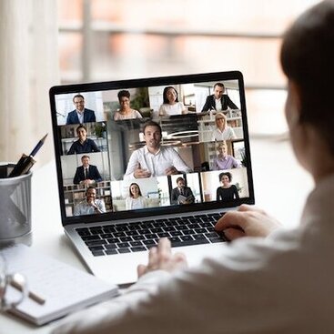 A close up shot of a person attending a 10-person video conference on a laptop.