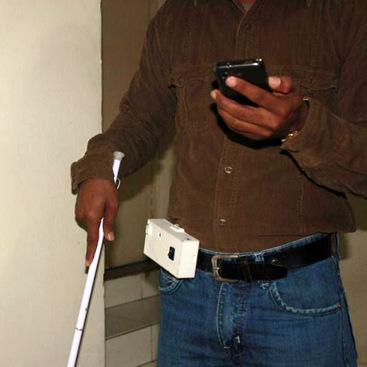 A blind person navigating in the building by listening to the instructions on the mobile phone. He is also wearing a device on the waist.